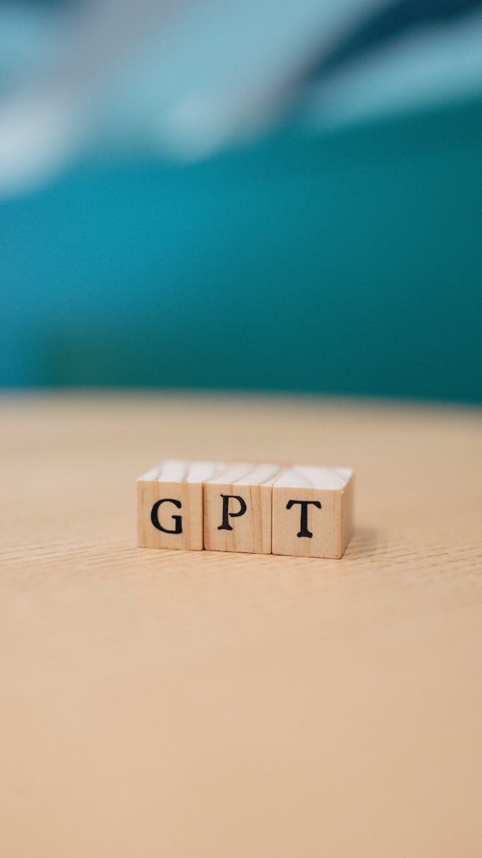Close-up of wooden blocks spelling GPT on a table with blurred background.